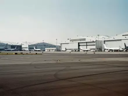 Weitläufiges Rollfeld vor einer Reihe von Flugzeughangars an einem Flughafen bei Tageslicht. - Foto: über boerse-global.de