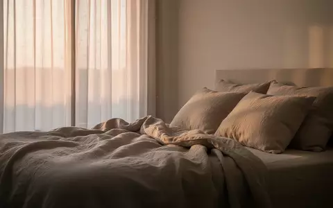 Ein ruhiges, minimalistisches Schlafzimmer bei Tagesanbruch mit weichem, natürlichem Licht, das auf ein ungemachtes Bett mit Leinenbettwäsche fällt. - Foto: über boerse-global.de