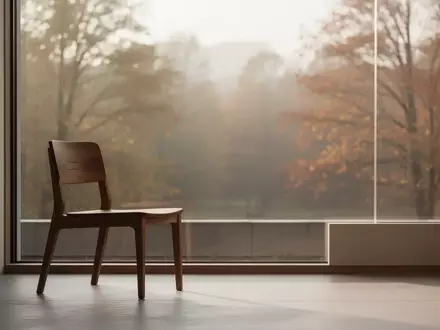 Ein minimalistischer Raum mit einem einzelnen leeren Holzstuhl vor einem Fenster mit Blick auf eine ruhige Naturlandschaft. - Foto: über boerse-global.de