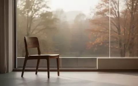Ein minimalistischer Raum mit einem einzelnen leeren Holzstuhl vor einem Fenster mit Blick auf eine ruhige Naturlandschaft. - Foto: über boerse-global.de