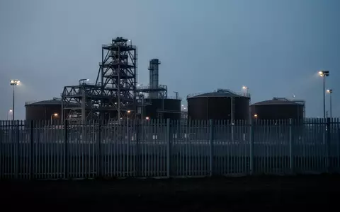Eine weitläufige Industrieanlage in der Dämmerung, umzäunt von einem hohen Metallzaun, als Symbol für erhöhte Sicherheitsvorkehrungen. - Foto: über boerse-global.de