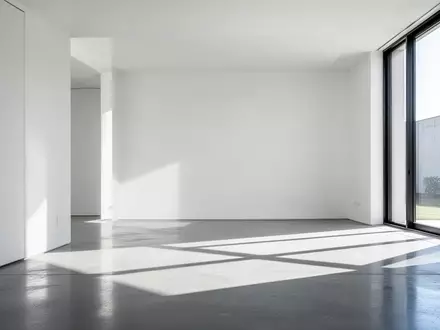 Ein minimalistischer Innenraum mit weißen Wänden und geometrischen Schattenwürfen auf einem Betonboden. - Foto: über boerse-global.de