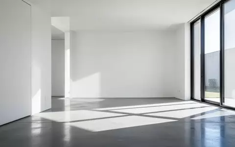 Ein minimalistischer Innenraum mit weißen Wänden und geometrischen Schattenwürfen auf einem Betonboden. - Foto: über boerse-global.de