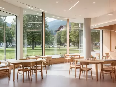 Ein heller, moderner Gemeinschaftsraum mit Holzmöbeln und Blick ins Grüne in einem österreichischen Gemeindezentrum. - Foto: über boerse-global.de