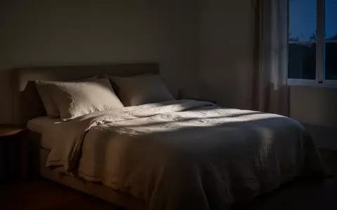 Ein minimalistisch eingerichtetes, ruhig beleuchtetes Schlafzimmer in den Abendstunden mit einem unberührten Bett. - Foto: über boerse-global.de