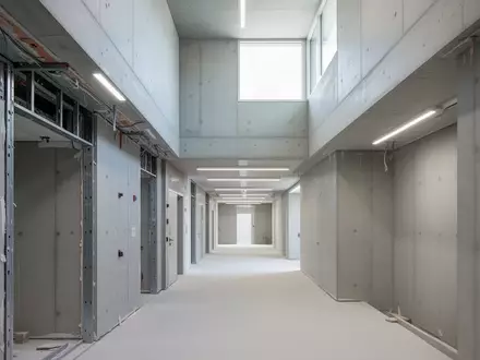 Ein heller, leerer Flur in einem öffentlichen Gebäude während der Renovierung mit sichtbaren architektonischen Strukturen. - Foto: über boerse-global.de