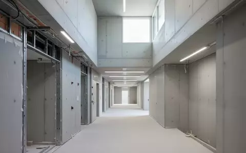 Ein heller, leerer Flur in einem öffentlichen Gebäude während der Renovierung mit sichtbaren architektonischen Strukturen. - Foto: über boerse-global.de
