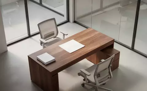Ein minimalistischer, leerer moderner Büroraum mit einem Holztisch und natürlichem Licht, der eine professionelle Arbeitsumgebung symbolisiert. - Foto: über boerse-global.de