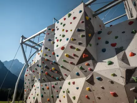 Moderne Außenkletterwand mit bunten Klettergriffen vor einem klaren Himmel in Oberbayern. - Foto: über boerse-global.de