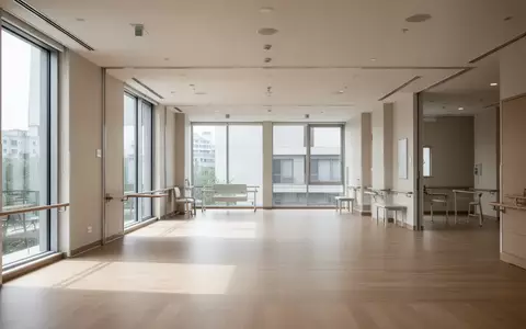 Ein heller, leerer Therapieraum mit Holzboden und großen Fenstern in einer modernen medizinischen Einrichtung. - Foto: über boerse-global.de
