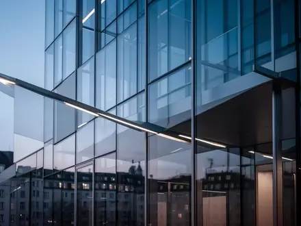 Moderne Glasfassade eines Bürogebäudes in München bei Dämmerung. - Foto: über boerse-global.de