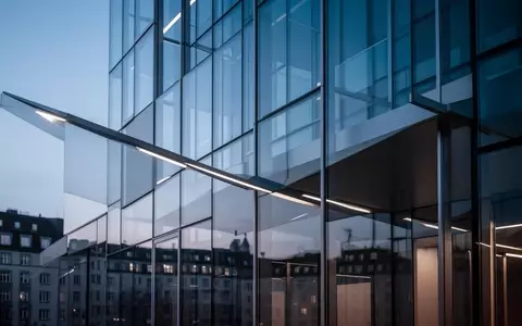 Moderne Glasfassade eines Bürogebäudes in München bei Dämmerung. - Foto: über boerse-global.de