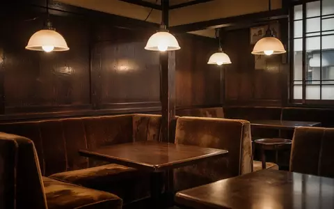 Ein stimmungsvoll beleuchteter Innenraum eines traditionellen japanischen Kaffeehauses mit dunklem Holz und Vintage-Mobiliar. - Foto: über boerse-global.de