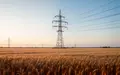 Ein Hochspannungsmast in einem weiten Feld bei Sonnenaufgang als Symbol für Energieinfrastruktur. - Foto: über boerse-global.de