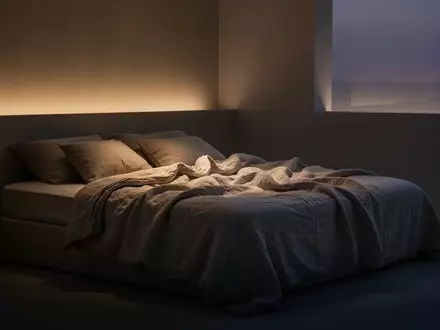 Ein minimalistisch eingerichtetes Schlafzimmer in der Dämmerung mit weicher Bettwäsche und sanfter Beleuchtung. - Foto: über boerse-global.de
