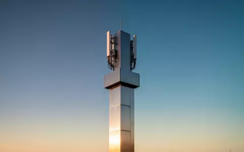 Ein moderner Mobilfunkmast vor einem klaren, blauen Himmel während der goldenen Stunde. - Foto: über boerse-global.de