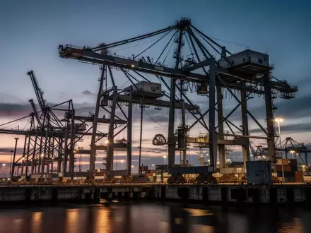 Moderne Hafenanlage mit Industriekränen und Umschlaginfrastruktur bei Dämmerung zur Veranschaulichung logistischer Prozesse. - Foto: über boerse-global.de