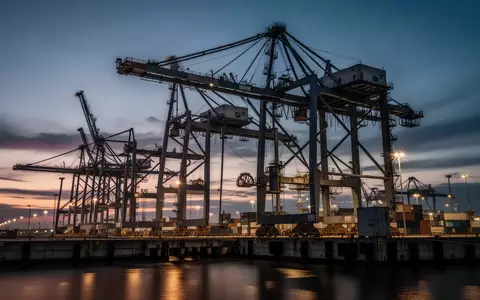 Moderne Hafenanlage mit Industriekränen und Umschlaginfrastruktur bei Dämmerung zur Veranschaulichung logistischer Prozesse. - Foto: über boerse-global.de