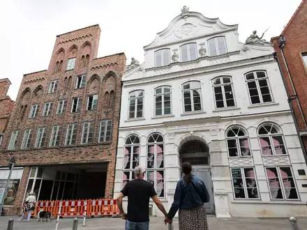 Passanten betrachten das geschlossene Buddenbrookhaus in der Lübecker Altstadt. - Foto: Christian Charisius/dpa