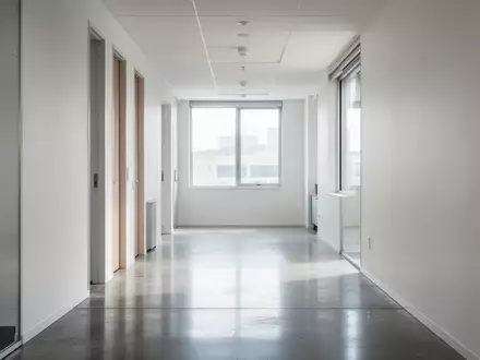 Ein heller, minimalistischer Büroflur mit poliertem Betonboden und weißer Wandgestaltung ohne Beschilderung. - Foto: über boerse-global.de