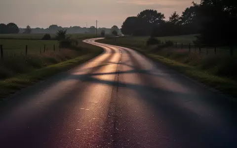 Eine leere, asphaltierte Landstraße in der Dämmerung, die sich durch eine ruhige Landschaft schlängelt. - Foto: über boerse-global.de
