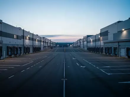 Leeres Logistikzentrum mit unbesetzten Laderampen und weitläufigem Betriebshof in der Morgendämmerung. - Foto: über boerse-global.de