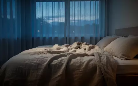 Ein minimalistisch eingerichtetes Schlafzimmer in der Abenddämmerung mit weichem Licht und gemütlichem Bett. - Foto: über boerse-global.de