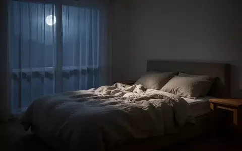 Ein minimalistisch eingerichtetes Schlafzimmer bei Nacht mit sanftem Mondlicht, das durch Vorhänge fällt und eine ruhige Atmosphäre schafft. - Foto: über boerse-global.de