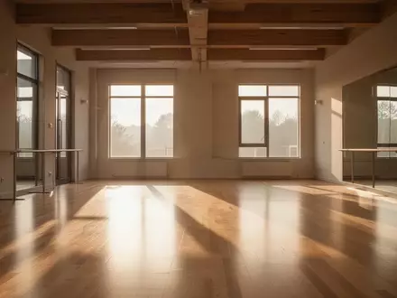 Ein lichtdurchfluteter, leerer Übungsraum mit Holzboden und großen Fenstern in einer minimalistischen Architektur. - Foto: über boerse-global.de