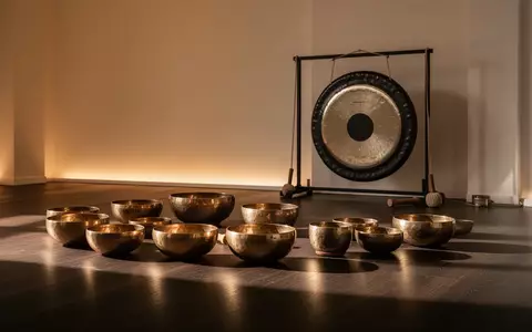 Ein minimalistischer Meditationsraum mit Klangschalen und einem Gong auf einem Holzboden in warmem Licht. - Foto: über boerse-global.de