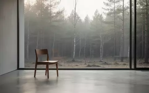 Ein minimalistischer, lichtdurchfluteter Raum mit einem leeren Holzstuhl vor einem Fenster mit Blick auf einen ruhigen Wald. - Foto: über boerse-global.de