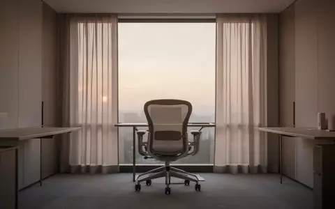 Ein ruhiger, leerer Büroarbeitsplatz mit ergonomischem Stuhl vor einem Fenster im sanften Morgenlicht. - Foto: über boerse-global.de