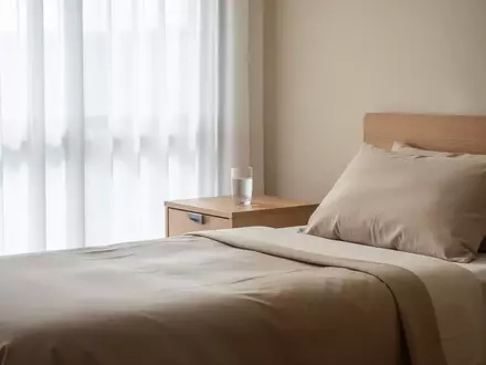 Ein ruhiges, sonnendurchflutetes Zimmer in einer Pflegeeinrichtung mit einem ordentlich gemachten Bett und schlichter Einrichtung. - Foto: über boerse-global.de