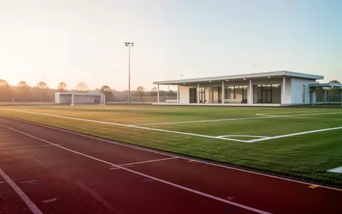 Ein leerer, moderner Sportplatz mit Laufbahn und Rasenfläche im sanften Morgenlicht. - Foto: über boerse-global.de