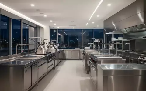 Moderne, minimalistische Edelstahl-Küchentechnik in einem hell erleuchteten Verkaufsraum bei Nacht. - Foto: über boerse-global.de