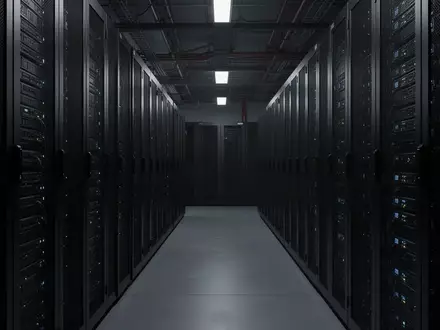 Dunkler, moderner Serverraum mit ordentlich aufgereihten Server-Racks und kühler Beleuchtung. - Foto: über boerse-global.de
