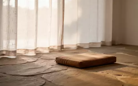 Ein minimalistischer, lichtdurchfluteter Meditationsraum mit Natursteinboden und einem einzelnen Holzkissen in ruhiger Atmosphäre. - Foto: über boerse-global.de