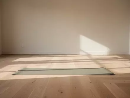Ein minimalistischer, sonnendurchfluteter Yogaraum mit einer einzelnen Matte auf einem hellen Holzboden. - Foto: über boerse-global.de