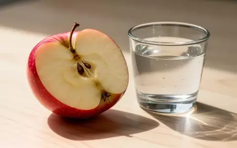 Ein aufgeschnittener Apfel und ein Glas Wasser auf einer hellen Holzoberfläche als Symbol für gesunde Ernährung. - Foto: über boerse-global.de