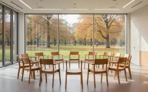 Ein heller, freundlicher Gruppenraum mit Stuhlkreis und Blick ins Grüne als Ort für soziale Begegnungen. - Foto: über boerse-global.de