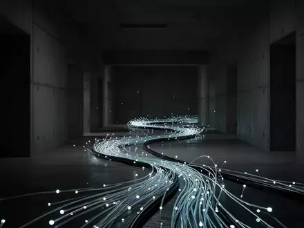 Ein glühendes Glasfaserkabel in einem dunklen, industriellen Betonkorridor als Symbol für digitale Sicherheitsrisiken. - Foto: über boerse-global.de