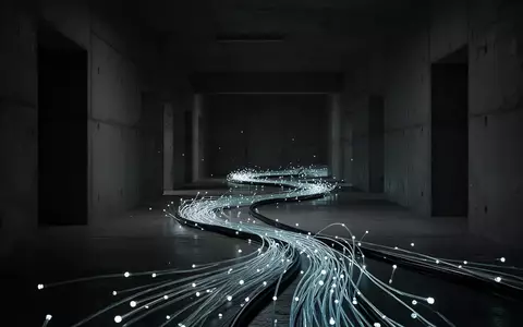Ein glühendes Glasfaserkabel in einem dunklen, industriellen Betonkorridor als Symbol für digitale Sicherheitsrisiken. - Foto: über boerse-global.de