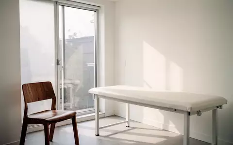 Ein heller, minimalistischer medizinischer Untersuchungsraum mit weichem Tageslicht und einer leeren Untersuchungsliege. - Foto: über boerse-global.de