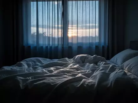 Ein ungemachtes Bett in einem ruhigen, in blaues Morgenlicht getauchten Schlafzimmer. - Foto: über boerse-global.de