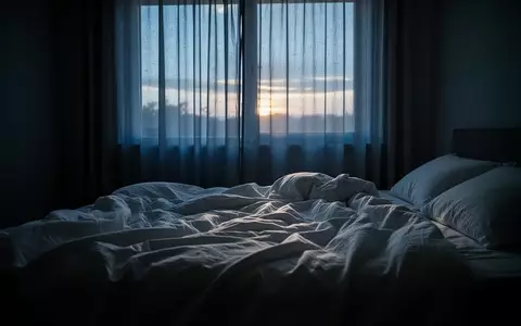 Ein ungemachtes Bett in einem ruhigen, in blaues Morgenlicht getauchten Schlafzimmer. - Foto: über boerse-global.de
