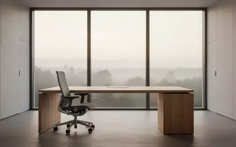 Ein leerer, modern gestalteter Büroarbeitsplatz mit einem Schreibtisch und einem ergonomischen Stuhl vor einem Fenster. - Foto: über boerse-global.de