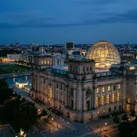 Das beleuchtete Reichstagsgebäude in Berlin bei Dämmerung unter einem klaren Abendhimmel. - Foto: über boerse-global.de