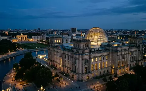 Das beleuchtete Reichstagsgebäude in Berlin bei Dämmerung unter einem klaren Abendhimmel. - Foto: über boerse-global.de