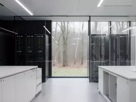 Ein minimalistisches, modernes Forschungslabor mit Serverinfrastruktur und Blick auf eine bewaldete Landschaft. - Foto: über boerse-global.de