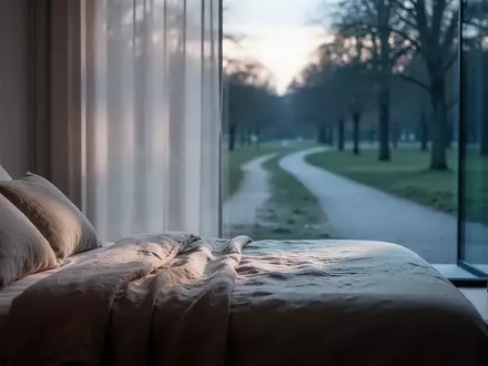 Ein minimalistisch eingerichtetes Schlafzimmer mit weichem Morgenlicht, das auf ein ordentlich gemachtes Bett fällt. - Foto: über boerse-global.de